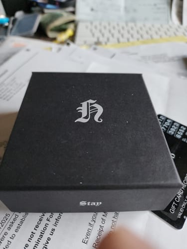 Customer showing the black box for the STRAY KIDS dominATE tour necklace, with a silver stylized 'h' logo on top.