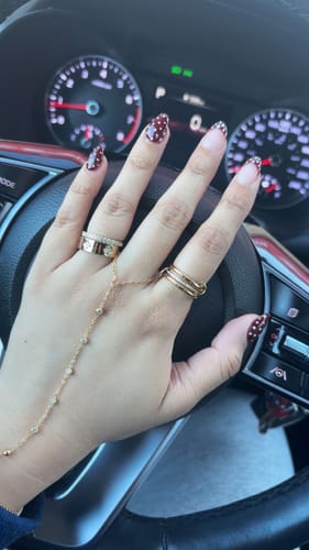 Customer wearing the gold Eloise Ring on their index finger, with their hand resting on a steering wheel.
