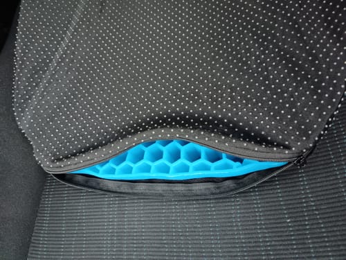 Vásárló zselés ülőpárnája egy autóülésen, melynek fekete huzata le van húzva, felfedve a kék méhsejtes betétet.