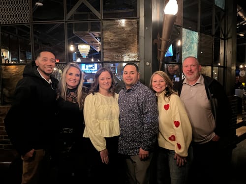 Reviewer in a group, wearing the cream Crazy In Love Sweater with red hearts on the sleeves.