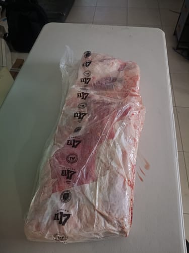 Cliente mostrando el costillar completo Ultimate Short Ribs en su empaque original sobre una mesa.