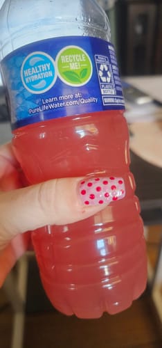 Customer holds a water bottle containing their prepared pink Migranium drink.