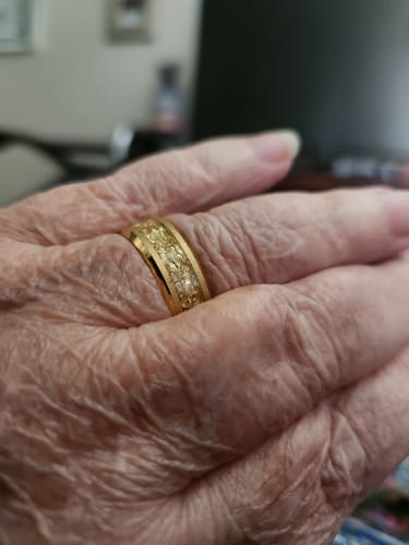 Close-up of a customer's hand wearing the gold Aureum ring, showing its textured foil inlay.