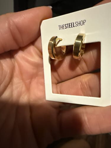 Customer holding the gold Beveled Edge Huggies Earrings in their packaging.