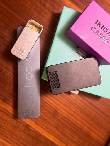 Customer's pill case bundle on a wooden table, showing an open silver case with pills and a closed black case.