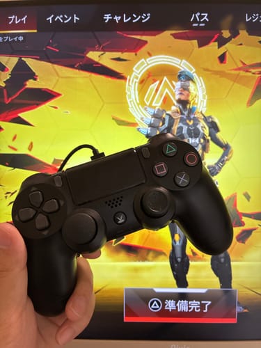 お客様が、ゲーム「Apex Legends」の画面を背景にPS4FireBirdコントローラーを手に持っている様子。