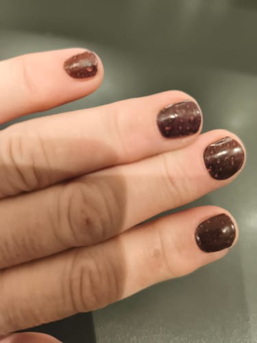 Rezensentin zeigt ihre Nägel mit den dunkelburgunderroten, gesprenkelten "Burgundy Rain" UV-Gelfolien.