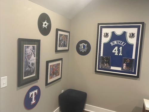 Customer's Dallas Mavericks wall art hanging on a game room wall with a framed jersey and other sports logos.