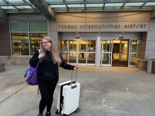 Reviewer wearing the black Disney "Midnight Mickeys" Classic Hoodie while standing outside an airport with luggage.