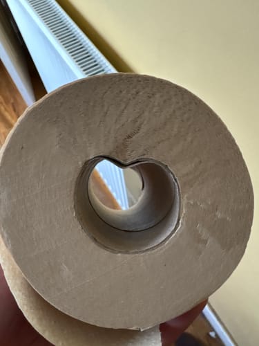 Reviewer's close-up of the unbleached toilet paper roll, highlighting a misshapen cardboard tube.