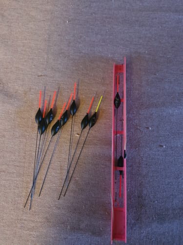 Klant toont een set AS1 dobbers met rode en gele antennes, naast een rode tuigenplank.