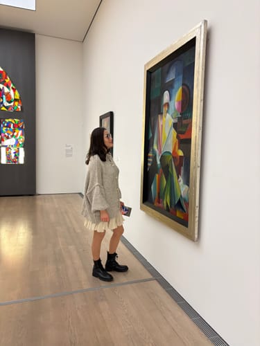 Kundin trägt das Bundle aus dem Oversized Cardigan 'CozyGlam' und dem Rock 'Summer' in einer Kunstgalerie.