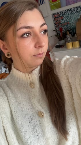 Nahaufnahme einer Kundin, die den cremefarbenen Bouclé Oversized Cardigan „CozyGlam“ mit goldenen Knöpfen trägt.