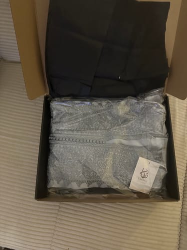 Reviewer unboxing the grey embroidered Mirelle caftan, shown packed in its original box.