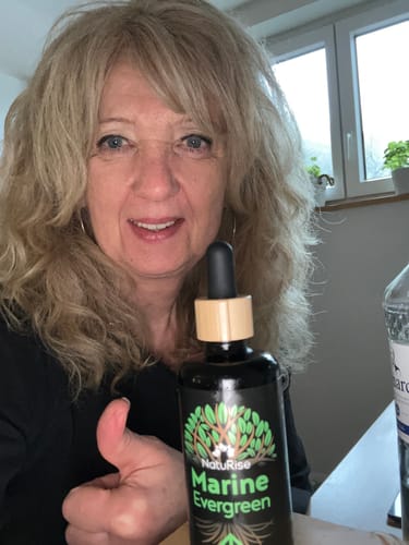 Kundin hält eine Flasche Omega 3 Algenöl und gibt einen Daumen hoch.