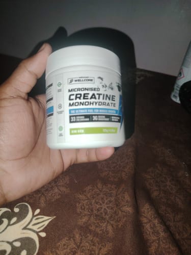 Customer holding the white tub of Wellcore Micronised Creatine Monohydrate in their hand.