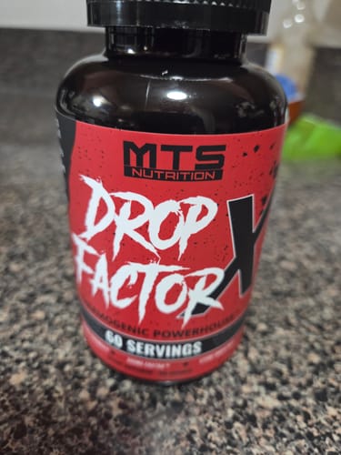 Customer's bottle of Drop Factor X fat burner, showing the red and black label on a counter.