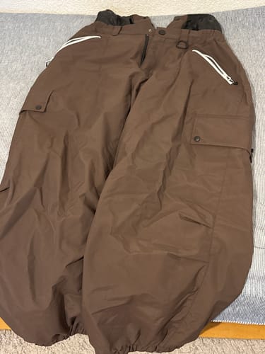 Reviewer's baggy snow pants in brown, laid out to display the pockets and zippers.