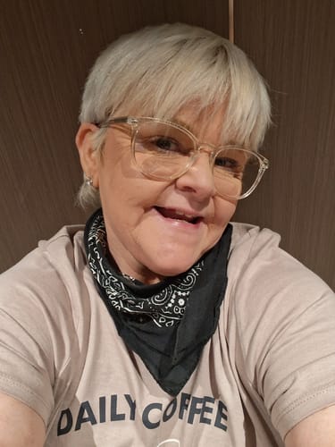 Reviewer with short hair and glasses smiling, happy with the results from her Monthly Beauty Box.