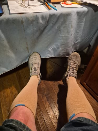A reviewer's first-person view of their legs wearing the tan Performance Eucalyptus Compression Socks.
