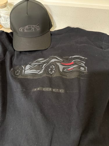 Customer's black 80Eighty DCG85 Shirt laid out next to a matching black hat, both showing a car graphic.
