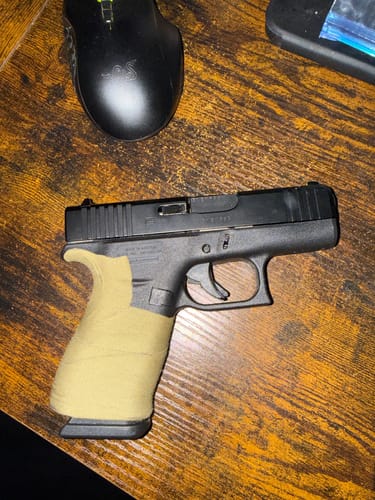 Reviewer's OD Green Raid Tape wrapped around the grip of a Glock handgun.