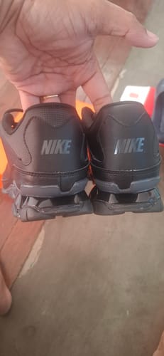 Customer holds up the heels of two black Nike Reax 8 TR shoes, showing that the Nike logos on the back do not match.