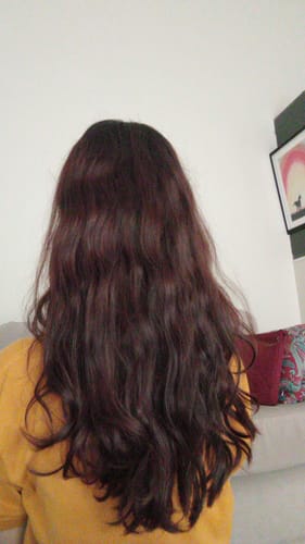 Reviewer shows their long, wavy, reddish hair after using the Leave-in Glossy Conditioner.
