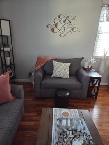 Reviewer's Afton floral pillow cover displayed on a grey armchair in a living room.