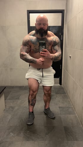 A muscular reviewer takes a mirror selfie showing their physique after using Hi-Tech Pharma Decabolin.
