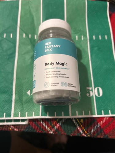 Customer's bottle of Her Fantasy Box Body Magic Capsules placed on a green football-themed mat.