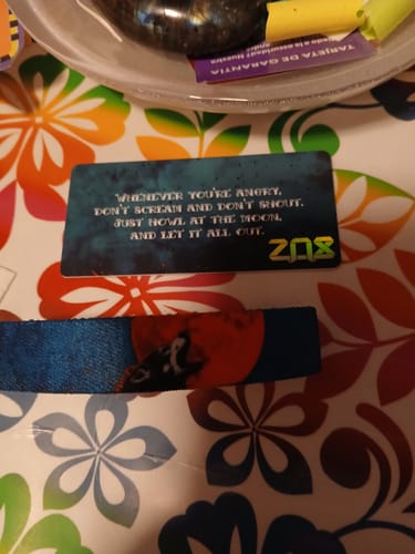 Reviewer's Howl At The Moon Bracelet and its matching quote card displayed on a colorful floral surface.