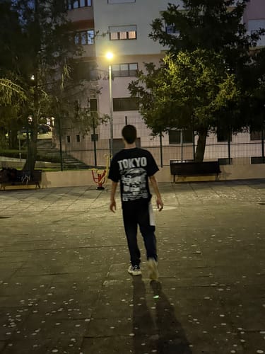 Customer from behind wearing the black Tokyo Drift T-Shirt while walking in a park at night.