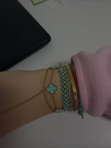 Kundin zeigt das Türkis Clover Armband am Handgelenk, gestapelt mit mehreren anderen goldenen und türkisen Armbändern.