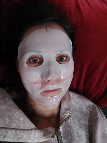 Rezensentin, die die weiße Kollagen-Boosting-Maske im Gesicht trägt.