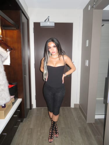 Reviewer standing in a hallway wearing the black Snake Heels with a black outfit, showing the tall lace-up style.