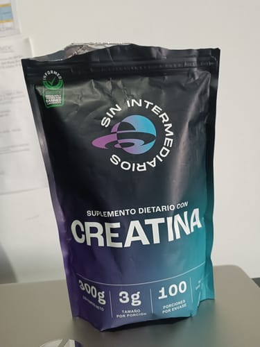 Cliente mostrando el empaque negro de la Creatina Monohidrato de Sin Intermediarios sobre una mesa.