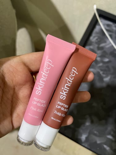 Customer holding two tubes of Peptide Lip Glaze in the shades Pink Rose and Teddy Kiss.