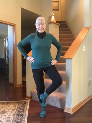 Reviewer showing the fit of her green Millie Long Sleeve top, worn over a black turtleneck indoors.