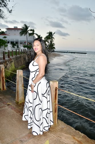 Customer wearing the white printed A-Line Maxi Dress with spaghetti straps on a pier by the sea.