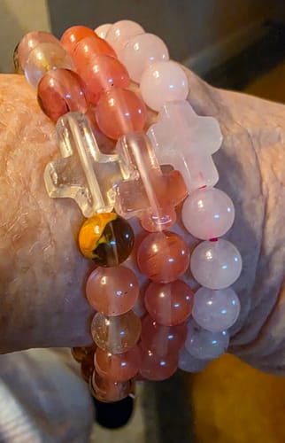 Reviewer's wrist showing three stacked stone bracelets, including the pink mix quartz Faithfully Bracelet.