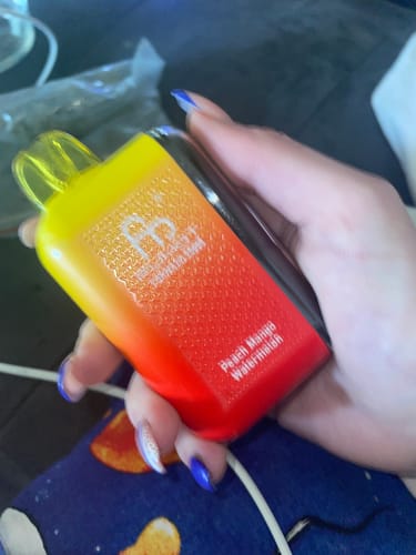 Kunde hält den gelb-roten RANDM TORNADO 20000 Vape mit Pfirsich-Mango-Wassermelonen-Geschmack.