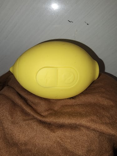 Reviewer's yellow lemon-shaped toy, showing its two control buttons, resting on a brown surface.