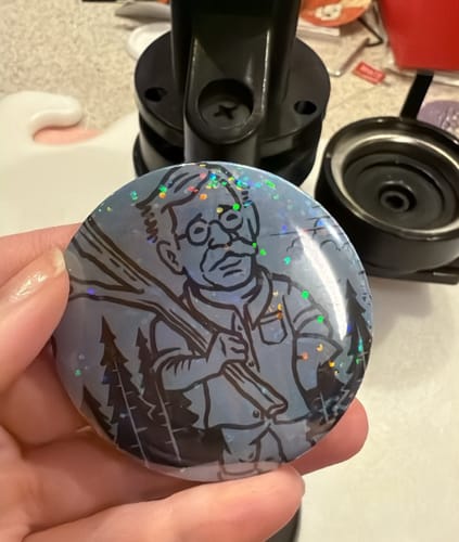 Reviewer holding a shiny, custom button they created using the Outpost – Wrapping Paper.