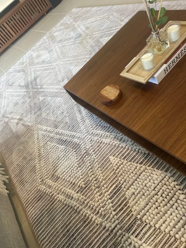 Customer's Mellow Mat in Desert Mosaic print shown in a living room under a dark wood coffee table.