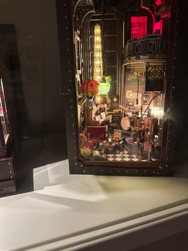 Customer's Eternal Midnight Paris Book Nook Kit displayed on a white shelf, with its warm interior lights on.