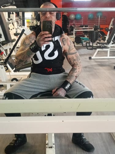 Reviewer sitting in a wide stance at the gym, wearing the black Notorious Lift Sumo Sole Gen 4 shoes.