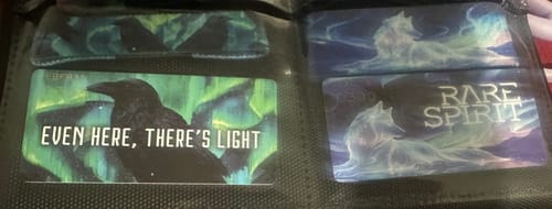 Reviewer's Aurora Aura Collection wristbands in a binder showing the "Even Here, There's Light" and "Rare Spirit" designs.