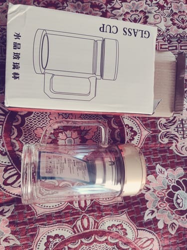 Customer's Double Wall Glass Mug lying next to its white packaging box on a patterned surface.