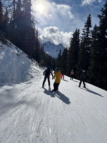 Customer and friends skiing on a sunny, snowy slope, a setting showing the wear-resistant snow pants in action.